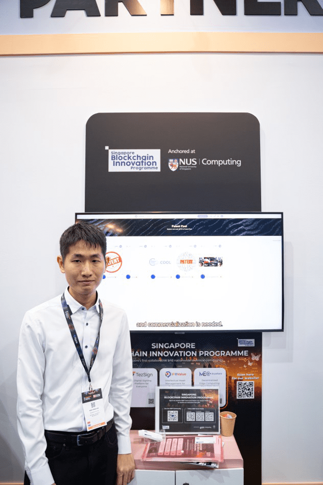 Dr Minh Ho standing next to SBIP Booth